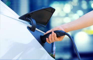 Person charging an electric vehicle in the city