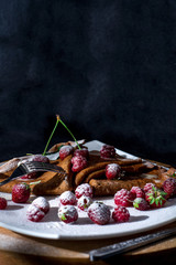  Pancakes on a black background with juicy berries and condensed milk. Pancakes on a white plate and wooden oak board. Food on a black background.