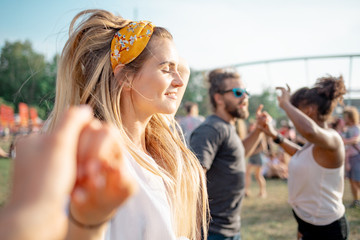 Obraz premium Beautiful young long haired woman dancing with friends outdoor at music festival