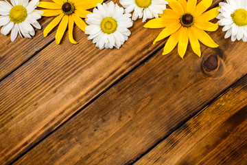 White daisies and garden flowers on a brown wooden table. Top view, copy space.