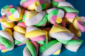 colorful marshmallow rope cut into pieces isolated on blue wood table