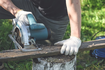 Man is cutting a wooden bar by a circular. Woodwork.