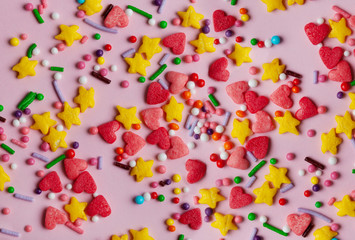 Colorful sprinkles on a pink background, top view with copy space.
