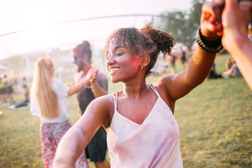 African American young woman with friends dancing at summer holi festival