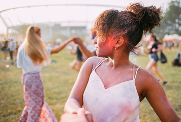 African American young woman with friends dancing at summer holi festival