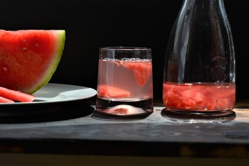 red water melon juice in a glass and jug at summer on black background