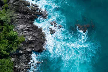 Poster Aerial drone top view of ocean's beautiful waves crashing on the rocky island coast © stryjek