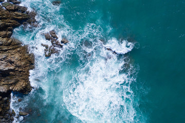 Fototapeta na wymiar Aerial drone view of ocean's beautiful waves crashing on the rocky island coast