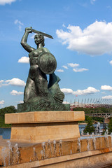 Fototapeta na wymiar Mermaid statue in Warsaw in Powiśle, in the background the Vistula and the National Stadium