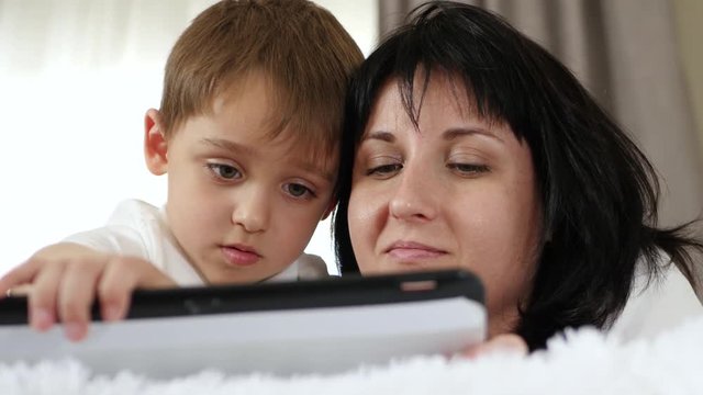 Mother and her child use a tablet computer to watch a movie and access the Internet.