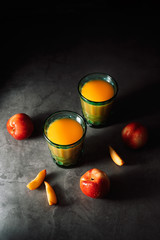 Still life of fresh delicious sweet nectarines with droplets of water and juice in turquoise vintage glasses on dark background. Low key.