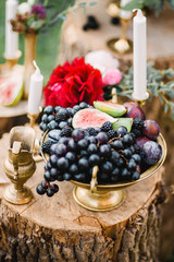 Obraz na płótnie Canvas Wedding decor of fruit, flowers and candles on a wooden stump