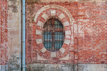 background of oval window with bars in an old brick building close up
