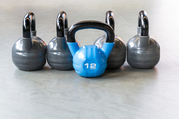 Naklejka na ściany i meble Sports, fitness or bodybuilding concept background. The composition of iron kettlebells on the floor in the gym.