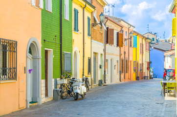 Typische italienische Altbauten mit farbenfrohen, bunten Wänden und traditionellen Häusern und Motorradrollern, die auf der Kopfsteinpflasterstraße im historischen Stadtzentrum von Rimini, Emilia-Romagna, Italien, geparkt sind