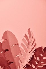 top view of decorative paper cut palm leaves on pink background