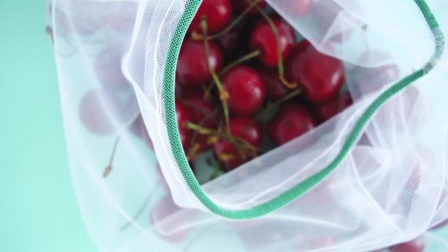 cherry in a reusable fabric transparent bag on a blue background in the fight against plastic