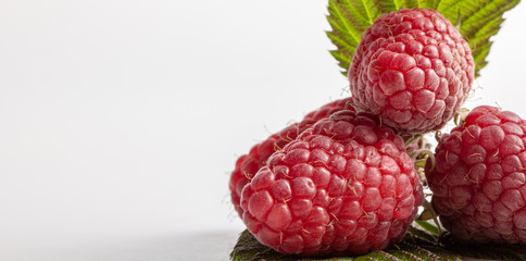 Group of three raspberries with leaves isolated on a white background