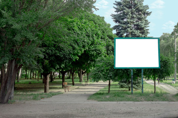 Billboard with copy space in park. Blank poster board among green trees and under blue sky. Banner...