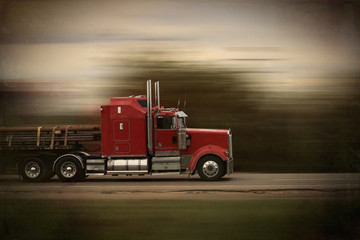 Bright red modern big rig semi truck and trailer in motion on a highway