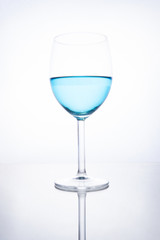 Blue cocktail in a glass on a white background with reflection
