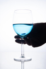 Blue cocktail in a glass on a white background with reflection