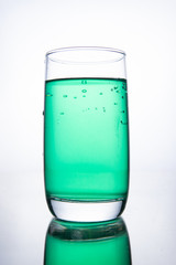 Green cocktail in a glass on a white background with reflection