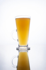 Light unfiltered beer poured into a steaming mug on a white background with reflection