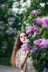 Beautiful big-eyed girl near the lilac tree.