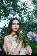 Beautiful big-eyed girl near the lilac tree.