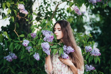Fototapeta premium Beautiful big-eyed girl near the lilac tree.
