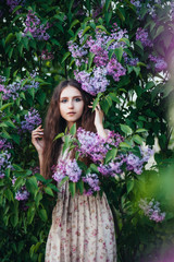 Obraz na płótnie Canvas Beautiful big-eyed girl near the lilac tree.