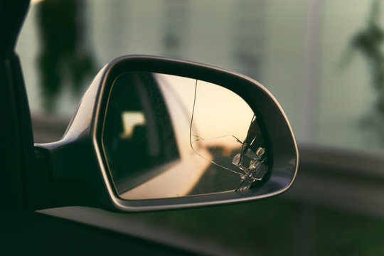 Side mirror of the car with a view back. Broken mirror close up.