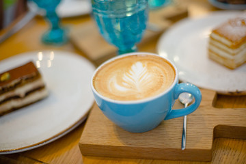Slice of sweet tasty Honey Cake Medovik and blue cup of cappuccino on the wooden table