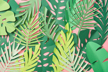 top view of scattered green palm leaves on pink background with copy space