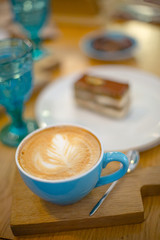 Slice of sweet tasty Honey Cake Medovik and blue cup of cappuccino on the wooden table