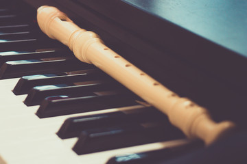 Block flute rest on a piano keyboard. classic music concept