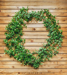 The branches, in the form of a wreath, with green leaves are beautifully laid out on a wooden brown background. Composition and concept, copy space. Spring flowering plant.