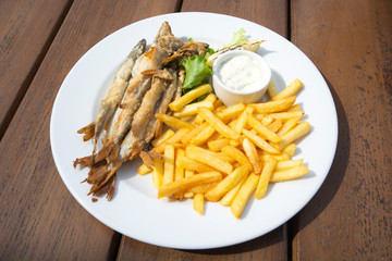 fried far Eastern smelt with potatoes and lemon on a wooden table
