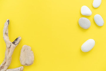 White sea pepples and sea snags on yellow background, flat lay, top view, copy space