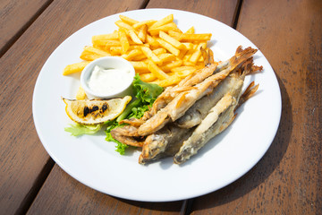 fried far Eastern smelt with potatoes and lemon on a wooden table