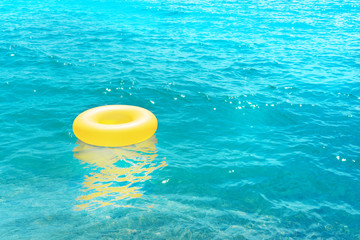 Fototapeta na wymiar a yellow rubber ring floats in the crystal blue sea in summer