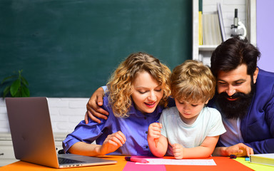 Young couple helping his son to make homework. Beginning of lessons. Education for children out of school. Parents feeling proud on progress of son. Family day. Family school partnership. School kids.