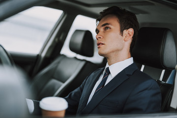 Handsome guy sitting behind wheel of his auto