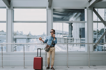 Man in sunglasses with coffee standing in corridor in airport