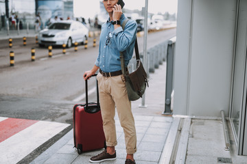 Young guy talking on smartphone near airport