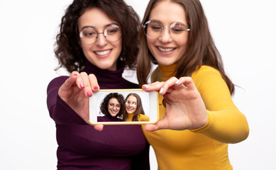 Female friends showing smartphone during selfie