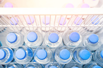 Rows of many transparent plastic bottles with drinking water supply in white refrigerator. Mineral...