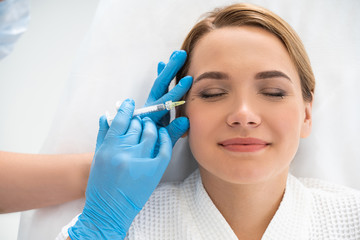Half length of young woman receiving a shot in cosmetology parlour