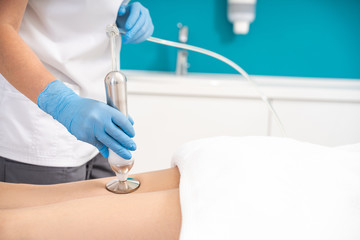 Massagist making vacuum roller massage with new apparatus for female client